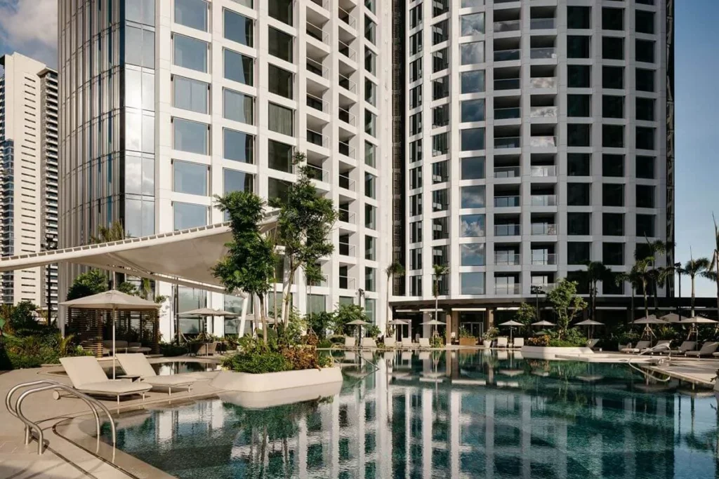 Luxury condominium towers with a landscaped swimming pool and lounge areas, showcasing wellness, comfort, and lifestyle-focused amenities
